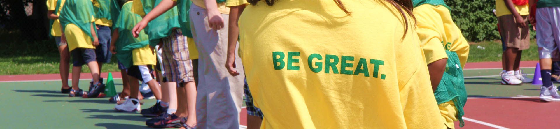 Image of kids at a relay race wearing tshirts that say "Be Great"